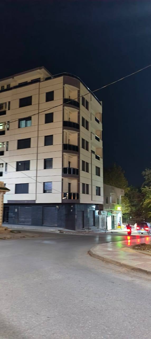 Immeuble achevé, façade crème et balcons noirs