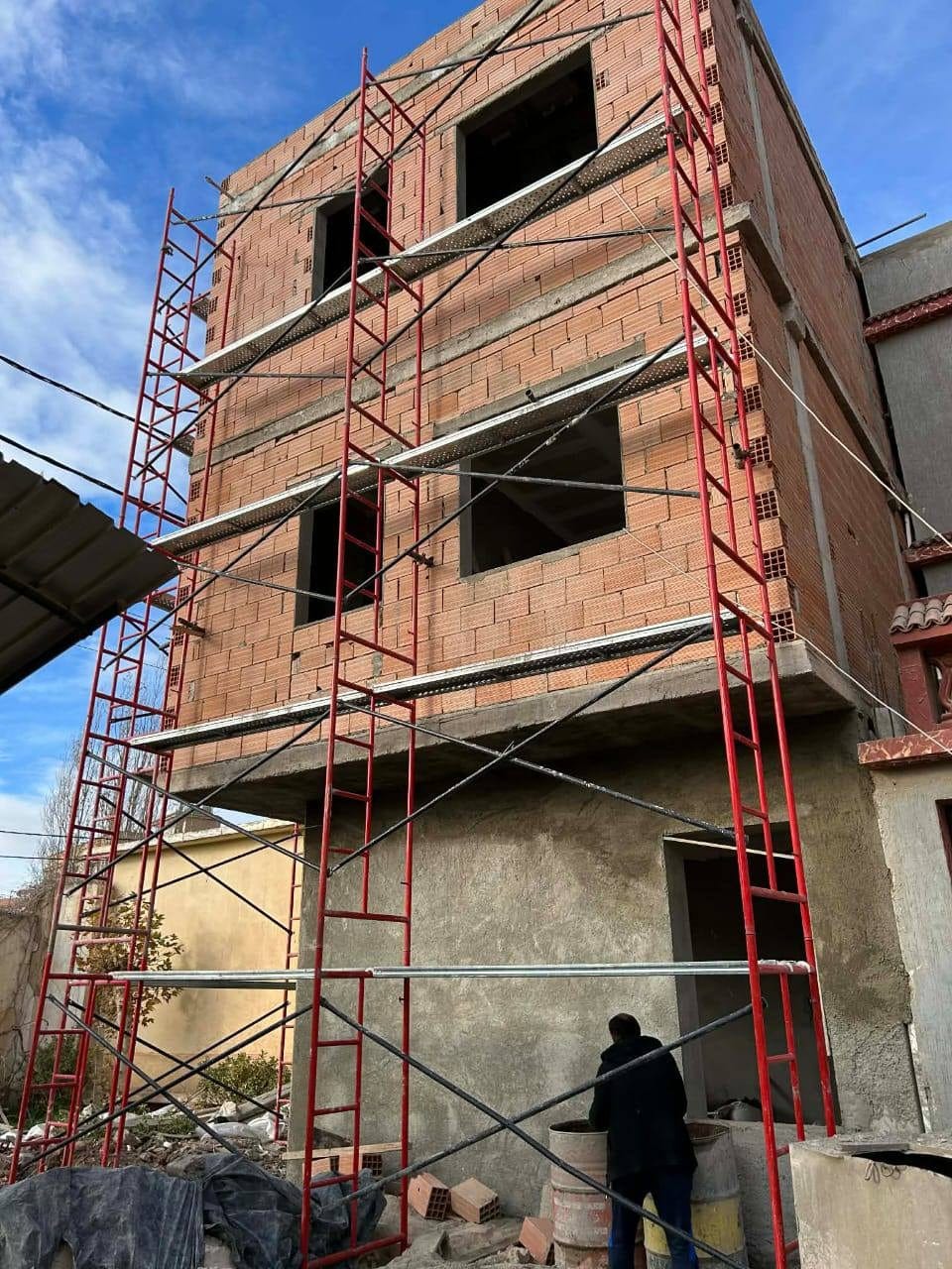 Immeuble en gros œuvre, briques apparentes et échafaudage